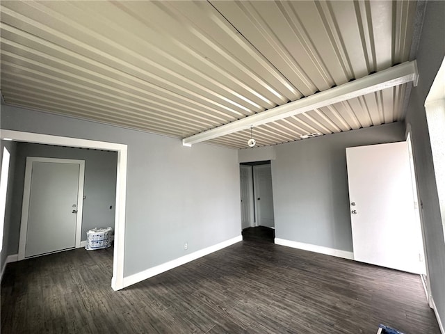 spare room featuring dark hardwood / wood-style floors and beamed ceiling