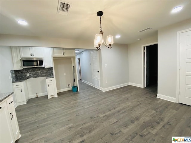 kitchen featuring decorative light fixtures, backsplash, white cabinetry, dark wood-type flooring, and dark stone counters