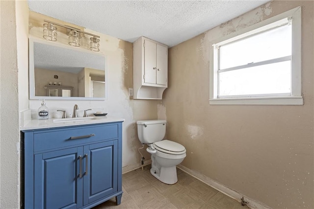 bathroom with a textured ceiling, toilet, vanity, baseboards, and tile patterned floors