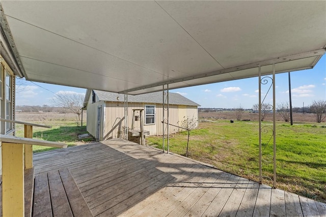 wooden deck with a rural view, a lawn, and an outdoor structure