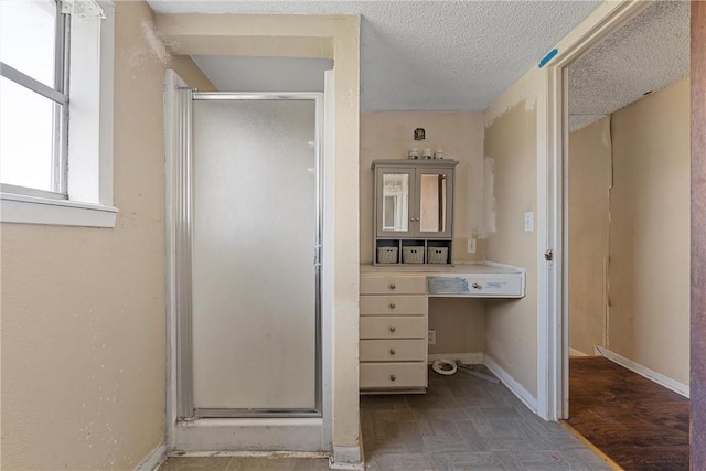 bathroom with a shower stall, baseboards, and a textured ceiling