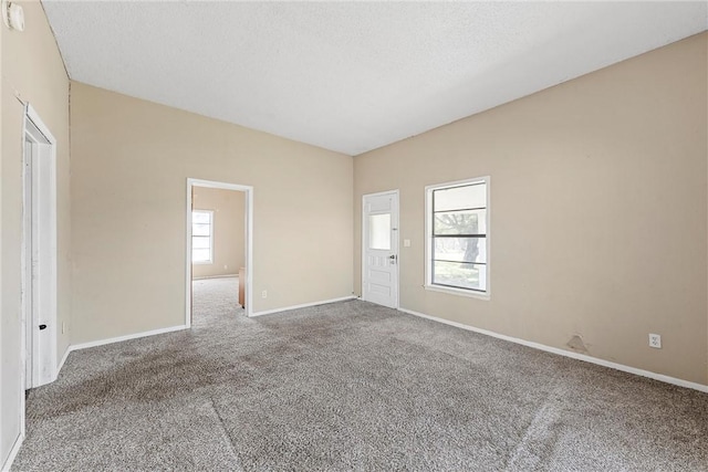 empty room featuring carpet flooring, a textured ceiling, and baseboards