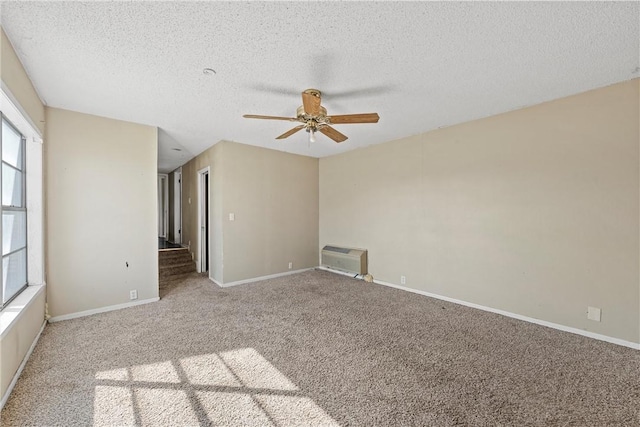 carpeted spare room with baseboards, ceiling fan, a textured ceiling, and heating unit