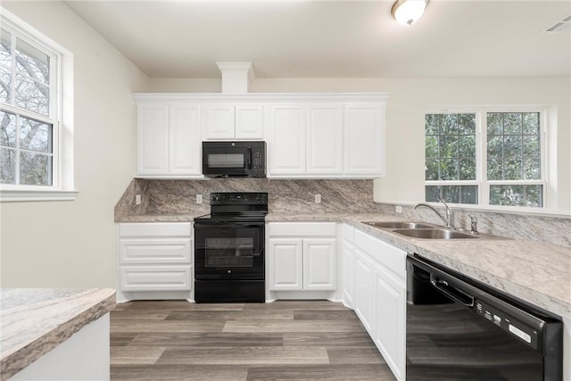 kitchen with black appliances, tasteful backsplash, a sink, and light countertops