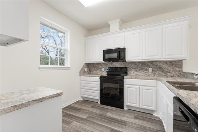 kitchen with light wood finished floors, backsplash, white cabinets, a sink, and black appliances