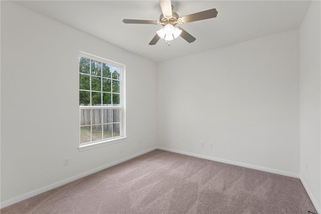 carpeted empty room featuring a ceiling fan and baseboards