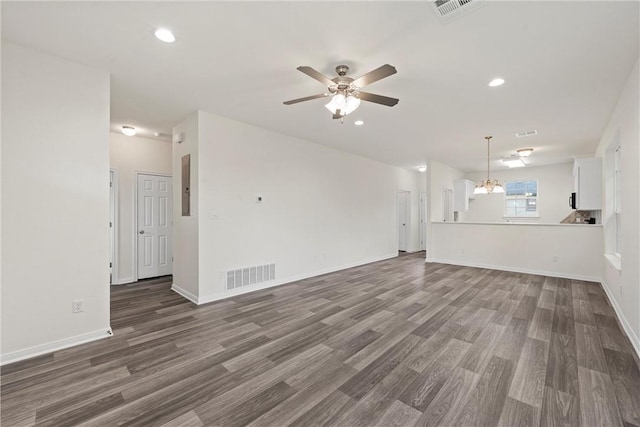 unfurnished living room featuring baseboards, visible vents, wood finished floors, ceiling fan with notable chandelier, and recessed lighting