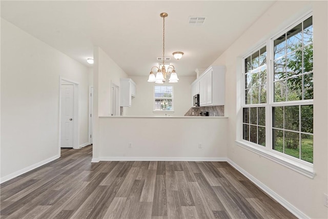 interior space featuring dark wood-style floors, an inviting chandelier, visible vents, and baseboards