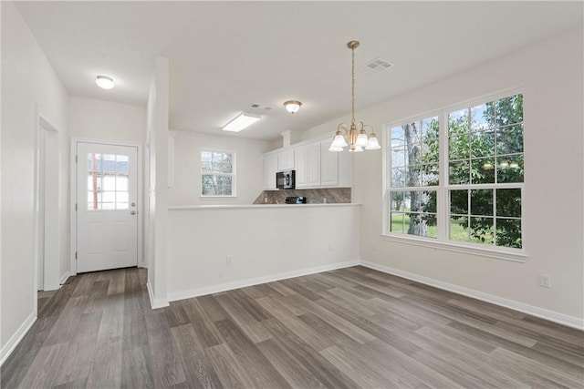 kitchen with visible vents, black microwave, white cabinets, and wood finished floors