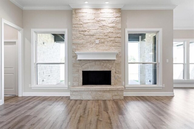 unfurnished living room with hardwood / wood-style floors, ornamental molding, and a fireplace