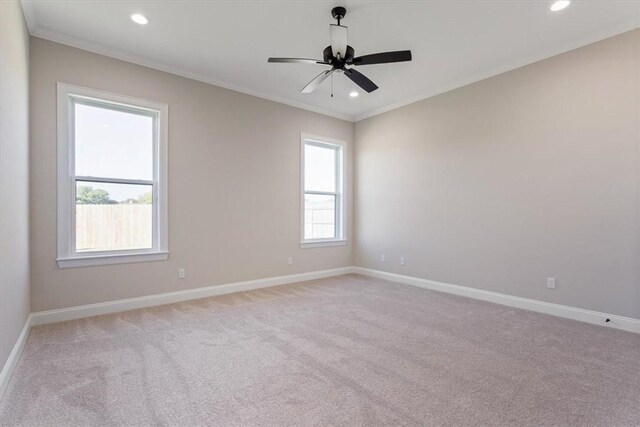 empty room with ceiling fan, light colored carpet, ornamental molding, and a wealth of natural light