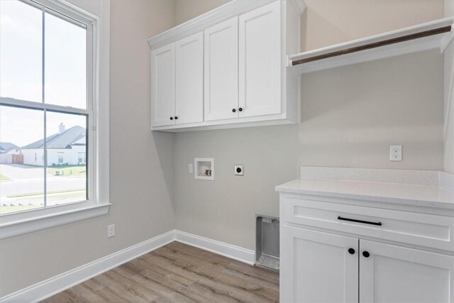 clothes washing area featuring hookup for an electric dryer, hookup for a washing machine, light hardwood / wood-style floors, and cabinets