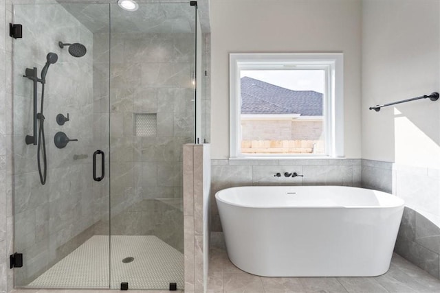 bathroom with separate shower and tub, tile patterned floors, and tile walls