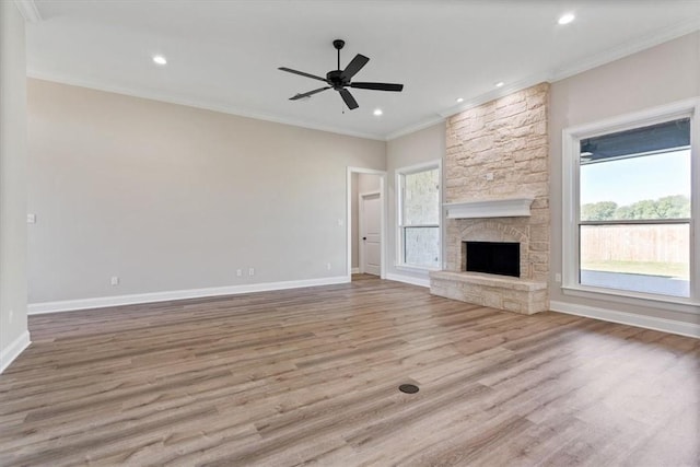 unfurnished living room featuring a stone fireplace, crown molding, light hardwood / wood-style flooring, and ceiling fan