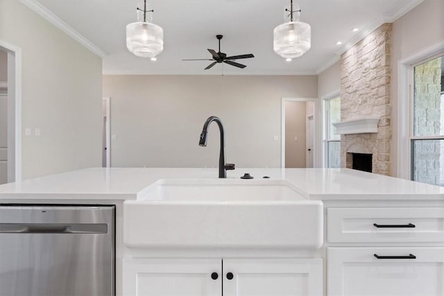 kitchen with a fireplace, white cabinets, stainless steel dishwasher, and sink