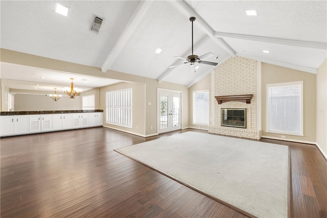 unfurnished living room with lofted ceiling with beams, dark wood-type flooring, a fireplace, and visible vents