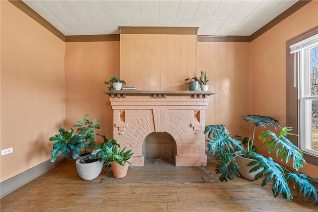 living area with ornamental molding, a brick fireplace, and light hardwood / wood-style floors