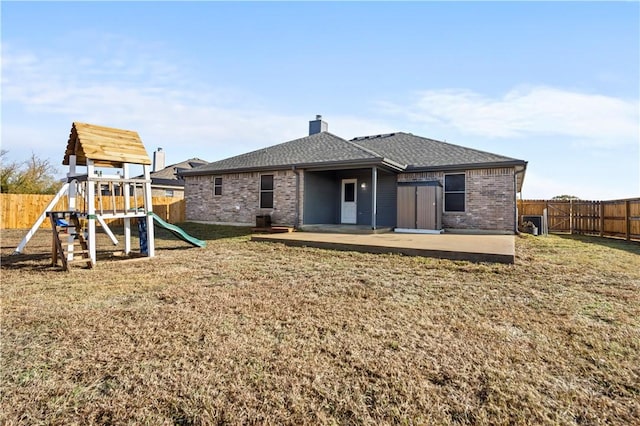 rear view of house with a playground, a yard, and a patio