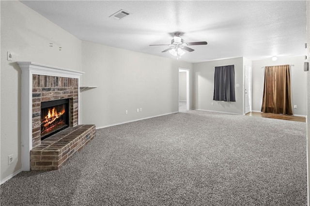 unfurnished living room featuring carpet, a textured ceiling, a brick fireplace, and ceiling fan