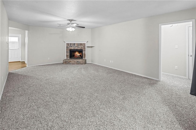 unfurnished living room with carpet flooring, a brick fireplace, and ceiling fan