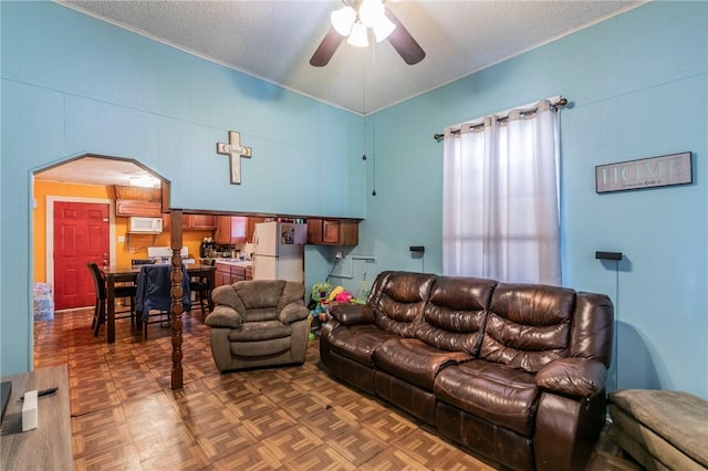 living room with ceiling fan, dark parquet floors, and a textured ceiling