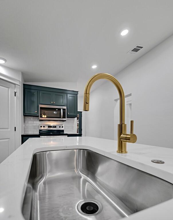 details featuring visible vents, recessed lighting, a sink, appliances with stainless steel finishes, and tasteful backsplash