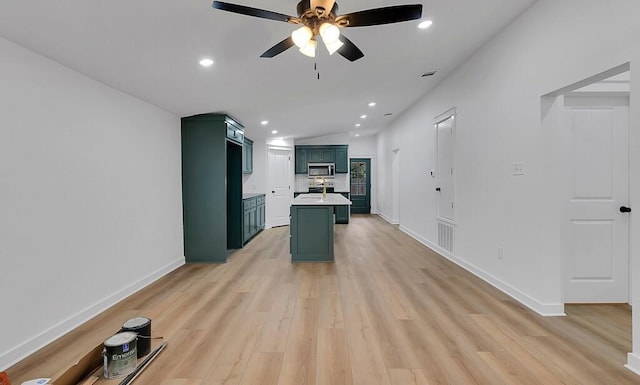 kitchen featuring light wood finished floors, stainless steel microwave, recessed lighting, and green cabinetry