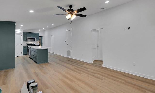 kitchen with stainless steel microwave, light countertops, visible vents, and light wood finished floors