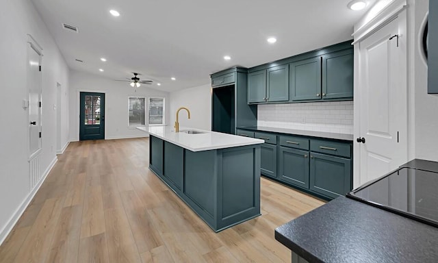 kitchen featuring lofted ceiling, recessed lighting, a sink, decorative backsplash, and light wood-style floors