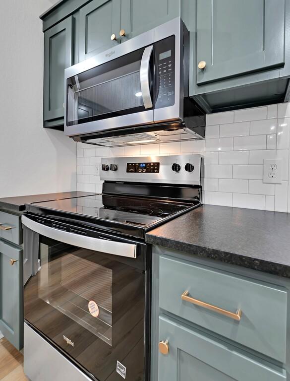 kitchen with backsplash, dark countertops, and appliances with stainless steel finishes