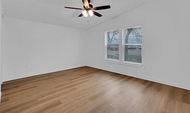 spare room featuring vaulted ceiling, baseboards, a ceiling fan, and wood finished floors