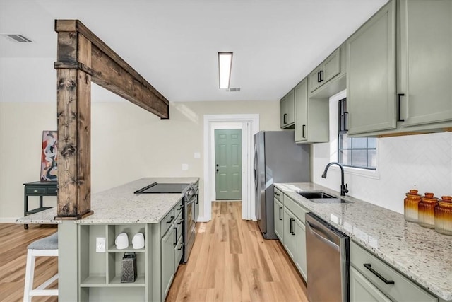 kitchen with stainless steel appliances, green cabinetry, a sink, and visible vents