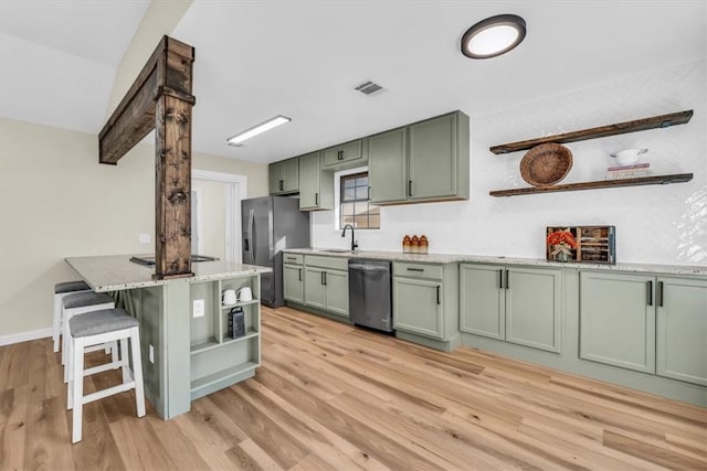 kitchen featuring open shelves, light wood finished floors, stainless steel appliances, green cabinets, and a sink