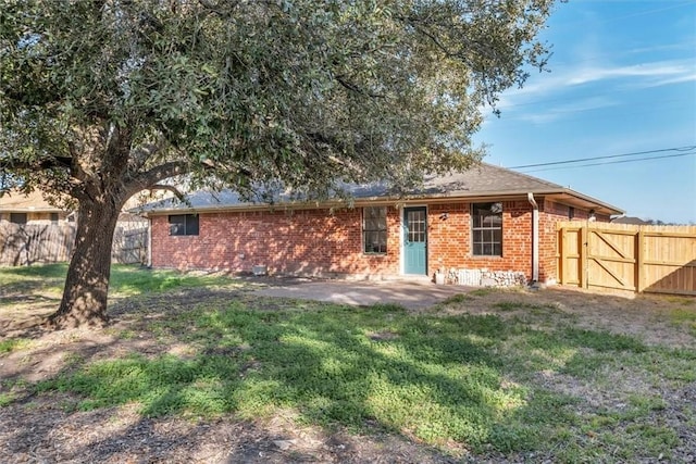 view of front facade featuring a patio, brick siding, a front yard, and fence