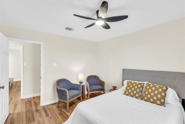 bedroom with a ceiling fan, wood finished floors, visible vents, and baseboards