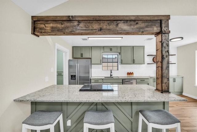 kitchen featuring stainless steel appliances, a breakfast bar, a sink, and a peninsula