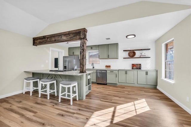 kitchen featuring lofted ceiling, appliances with stainless steel finishes, a breakfast bar area, a peninsula, and a sink