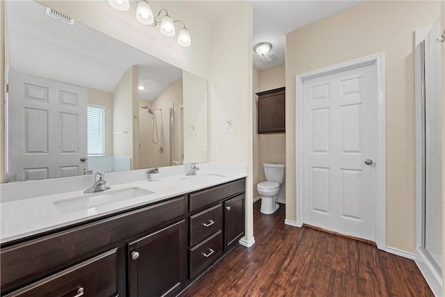 bathroom with wood-type flooring, toilet, vanity, and a shower with shower door