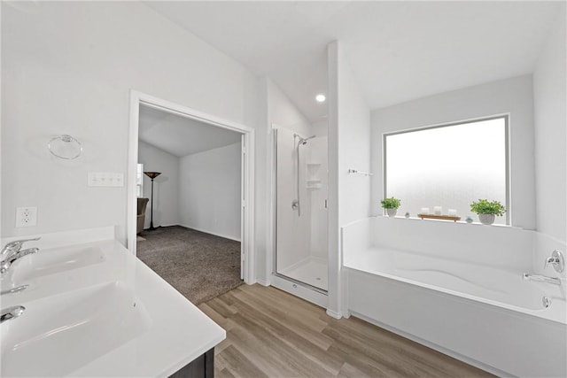 bathroom featuring wood-type flooring, vanity, separate shower and tub, and lofted ceiling