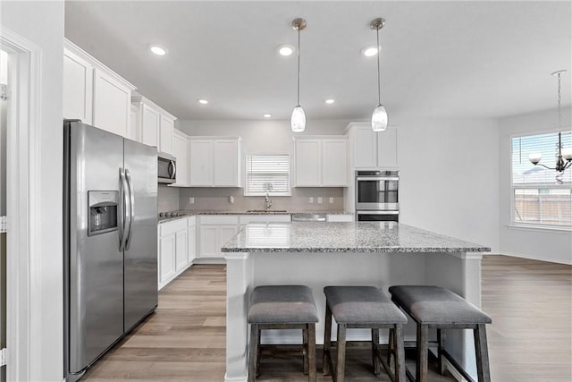 kitchen featuring white cabinets, a kitchen island, appliances with stainless steel finishes, and pendant lighting