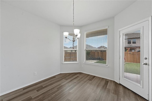 unfurnished dining area featuring wood-type flooring and an inviting chandelier