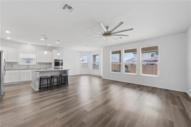 unfurnished living room featuring ceiling fan, sink, and dark wood-type flooring