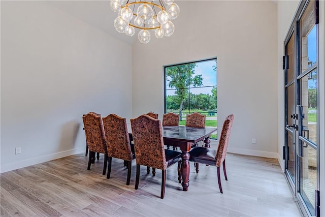 dining area with a healthy amount of sunlight, a chandelier, and light hardwood / wood-style flooring