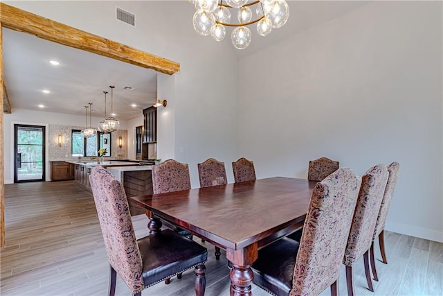 dining space with sink, light hardwood / wood-style floors, and a chandelier