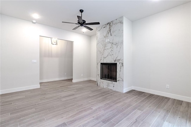 unfurnished living room featuring ceiling fan, a fireplace, and light hardwood / wood-style flooring