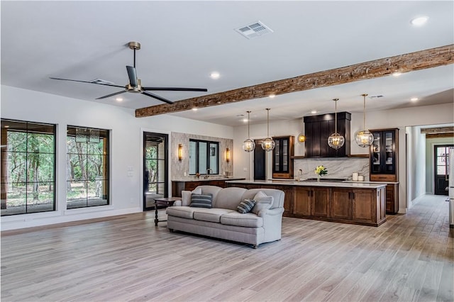 living room featuring beam ceiling, ceiling fan, a healthy amount of sunlight, and light hardwood / wood-style floors