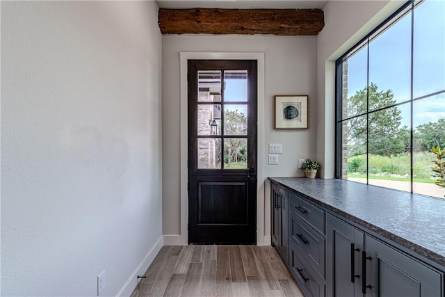 doorway to outside featuring beam ceiling and light hardwood / wood-style flooring