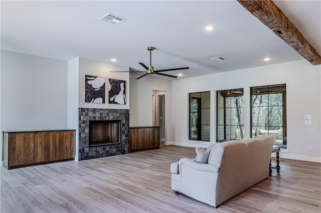 living room with ceiling fan, a fireplace, light hardwood / wood-style floors, and beam ceiling