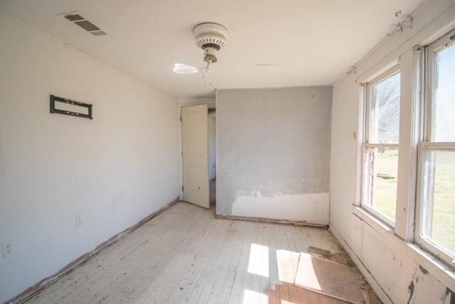 unfurnished room featuring light wood-style flooring, plenty of natural light, and visible vents