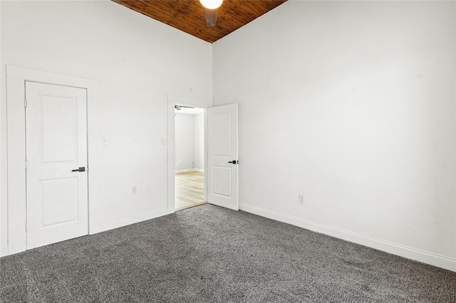 carpeted empty room featuring high vaulted ceiling, ceiling fan, and wooden ceiling